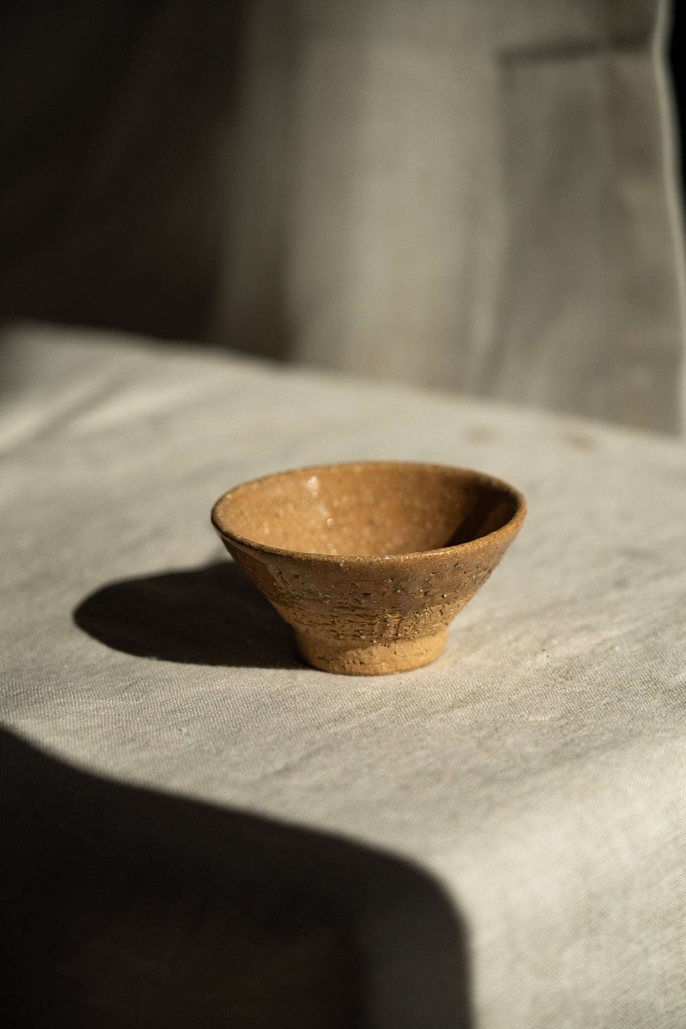 Handmade small yellow stoneware tea cup with white and grey speckles, glazed interior, and textured exterior