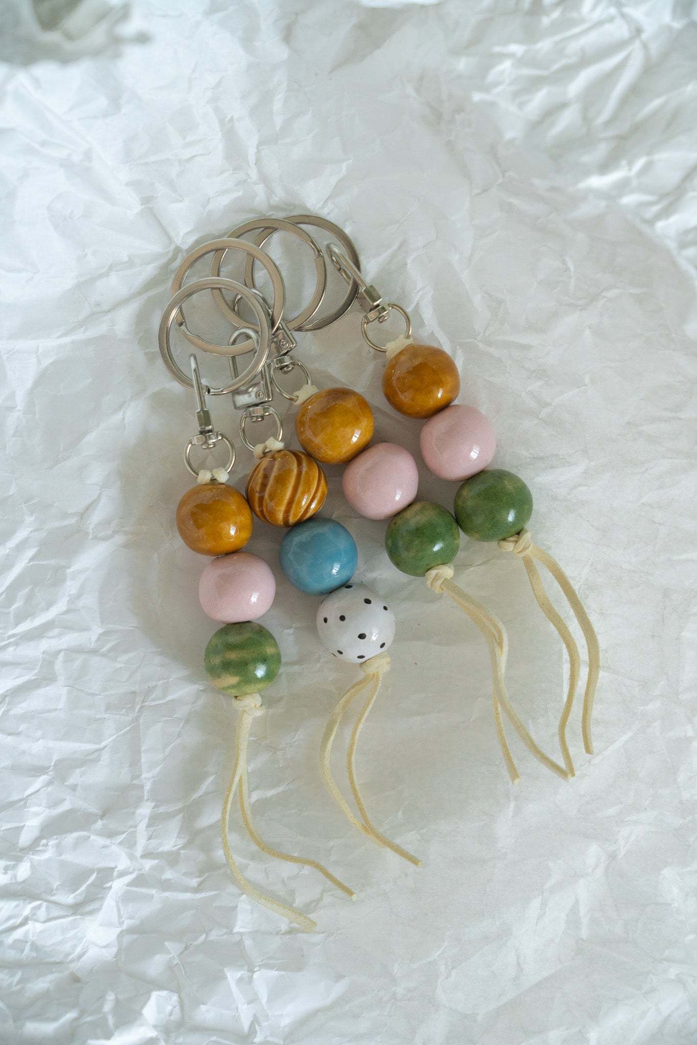 Handmade ceramic keychain with polka dot beads in white, blue, and caramel on leather cord with silver hardware