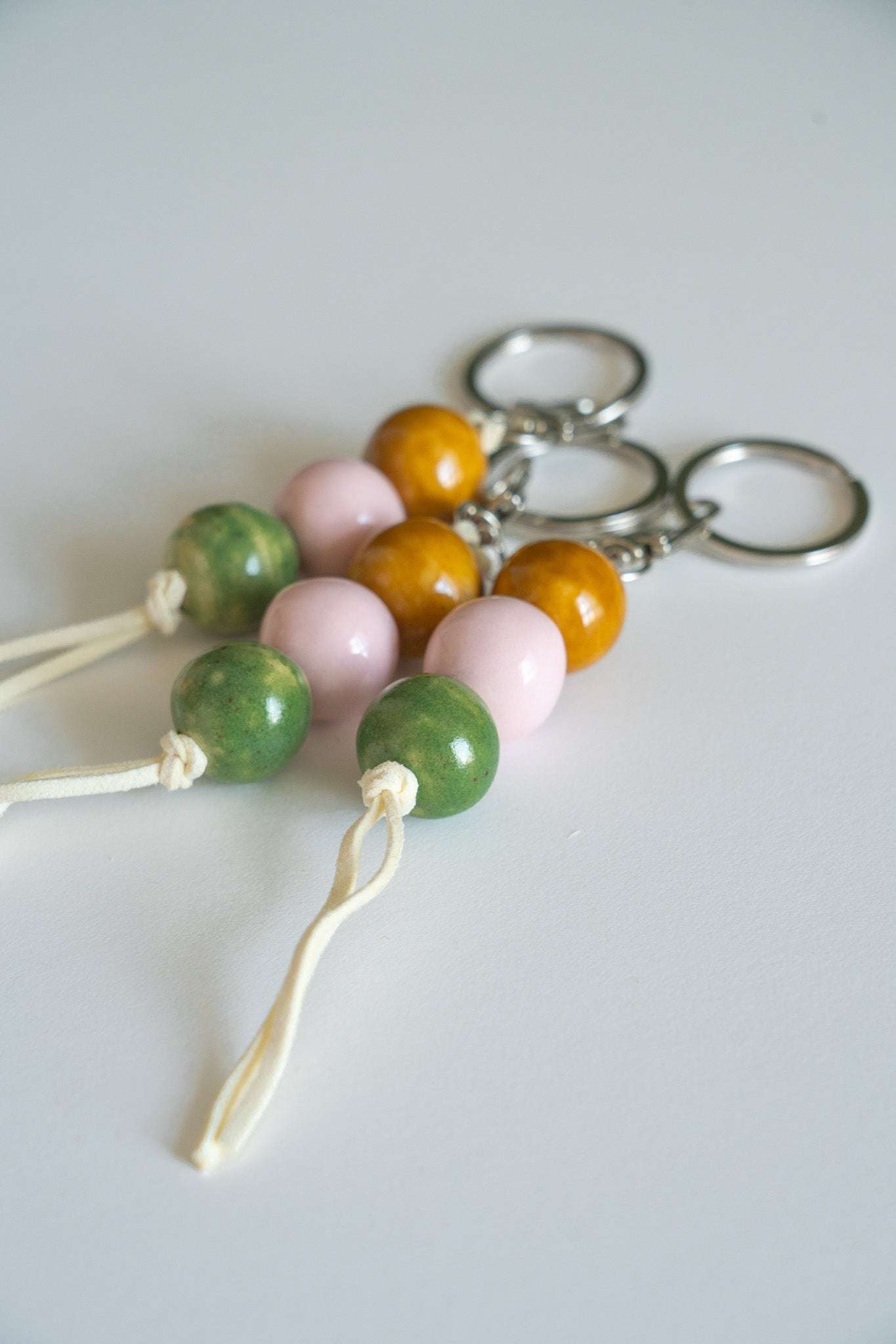 Handmade ceramic keychain with pastel pink, earthy green, and caramel beads on leather cord with silver hardware