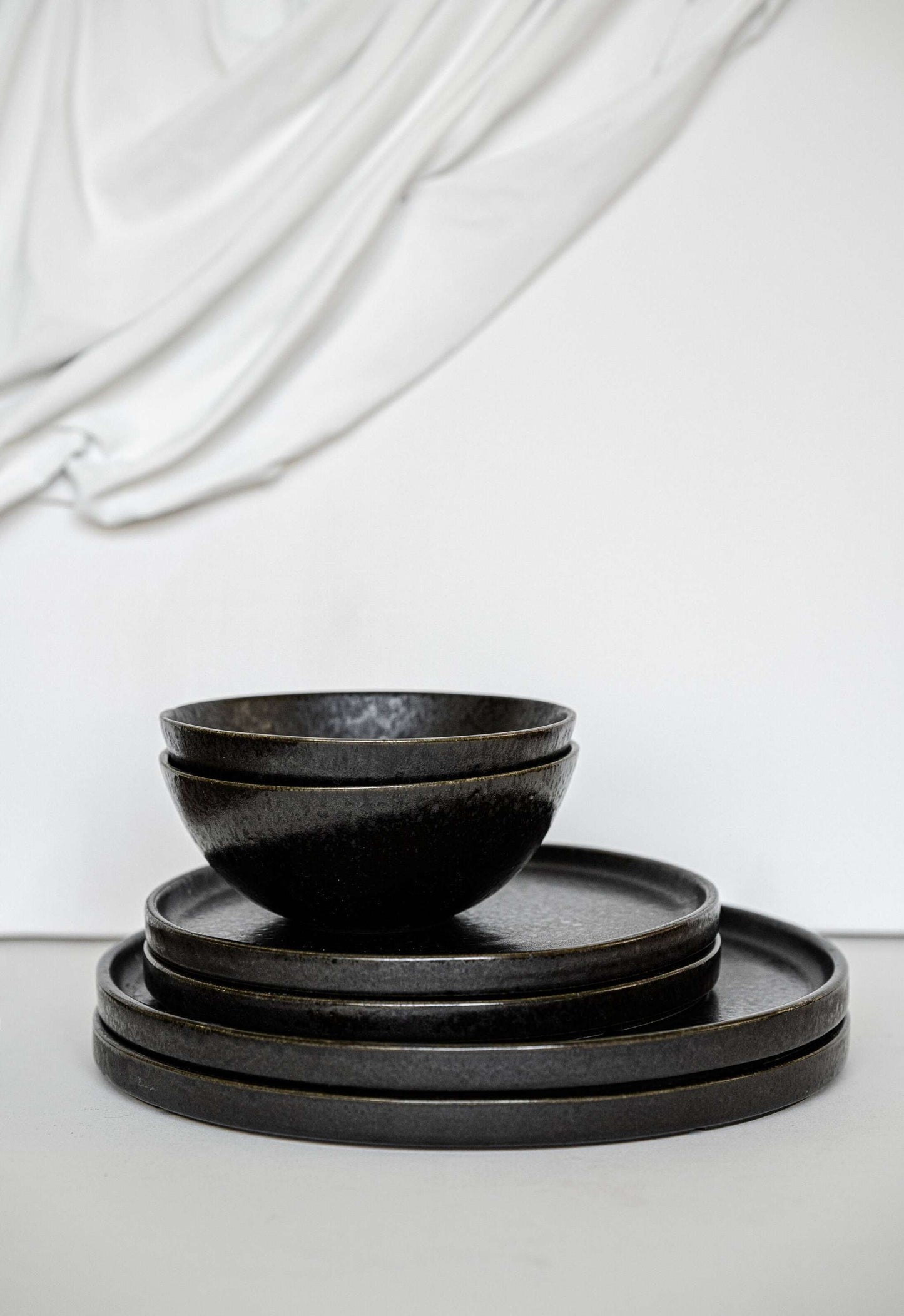 Black stoneware dinner plates with glossy speckled glaze and organic rims
