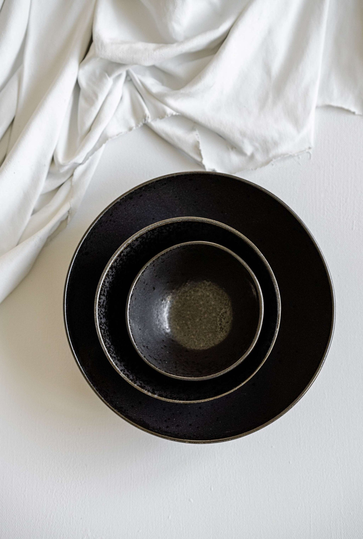 Matte black stoneware everyday bowl with glossy speckles and organic curves, handmade in Portugal
