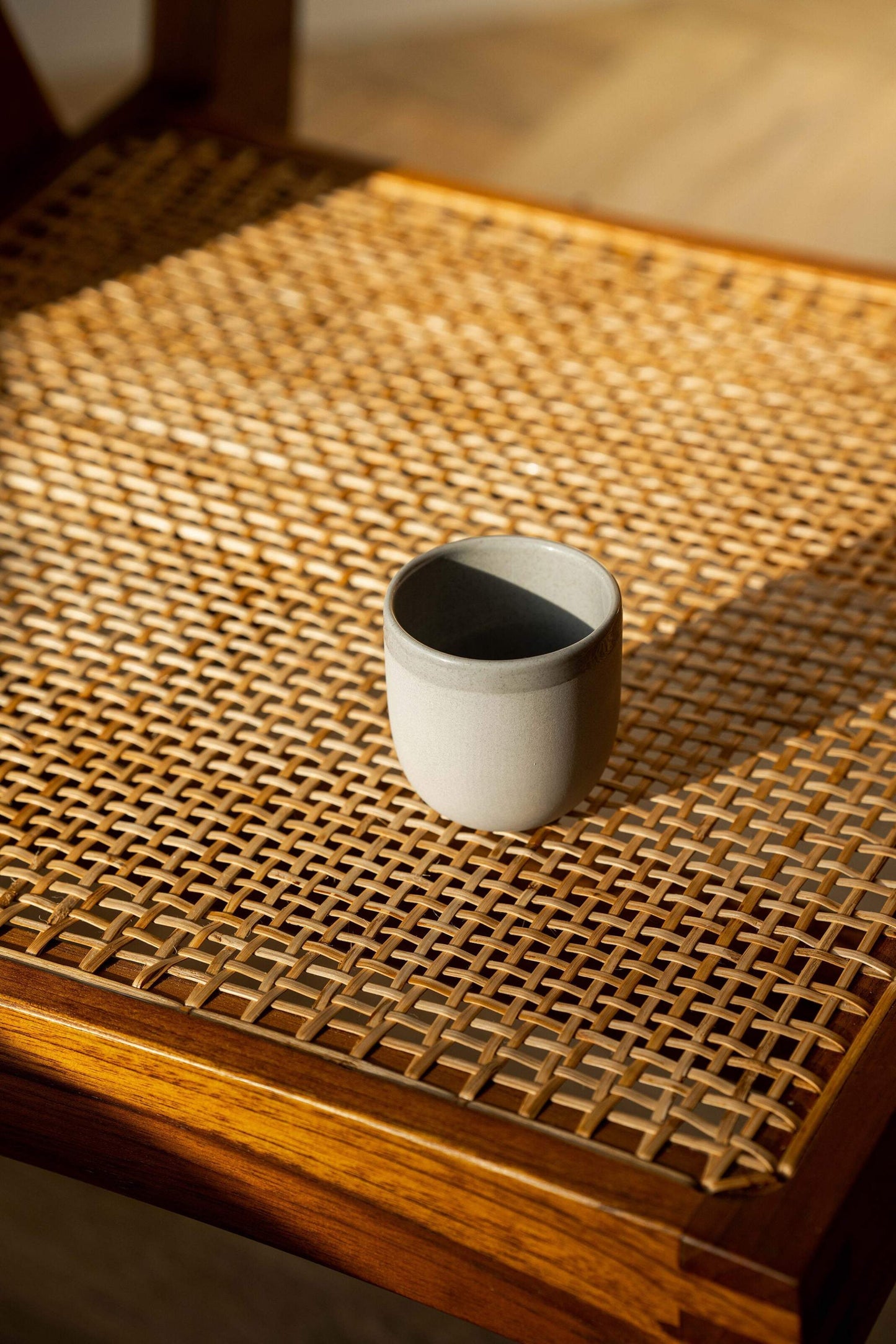 Handmade porcelain espresso cup with exposed clay and glossy glaze against gray sky background
