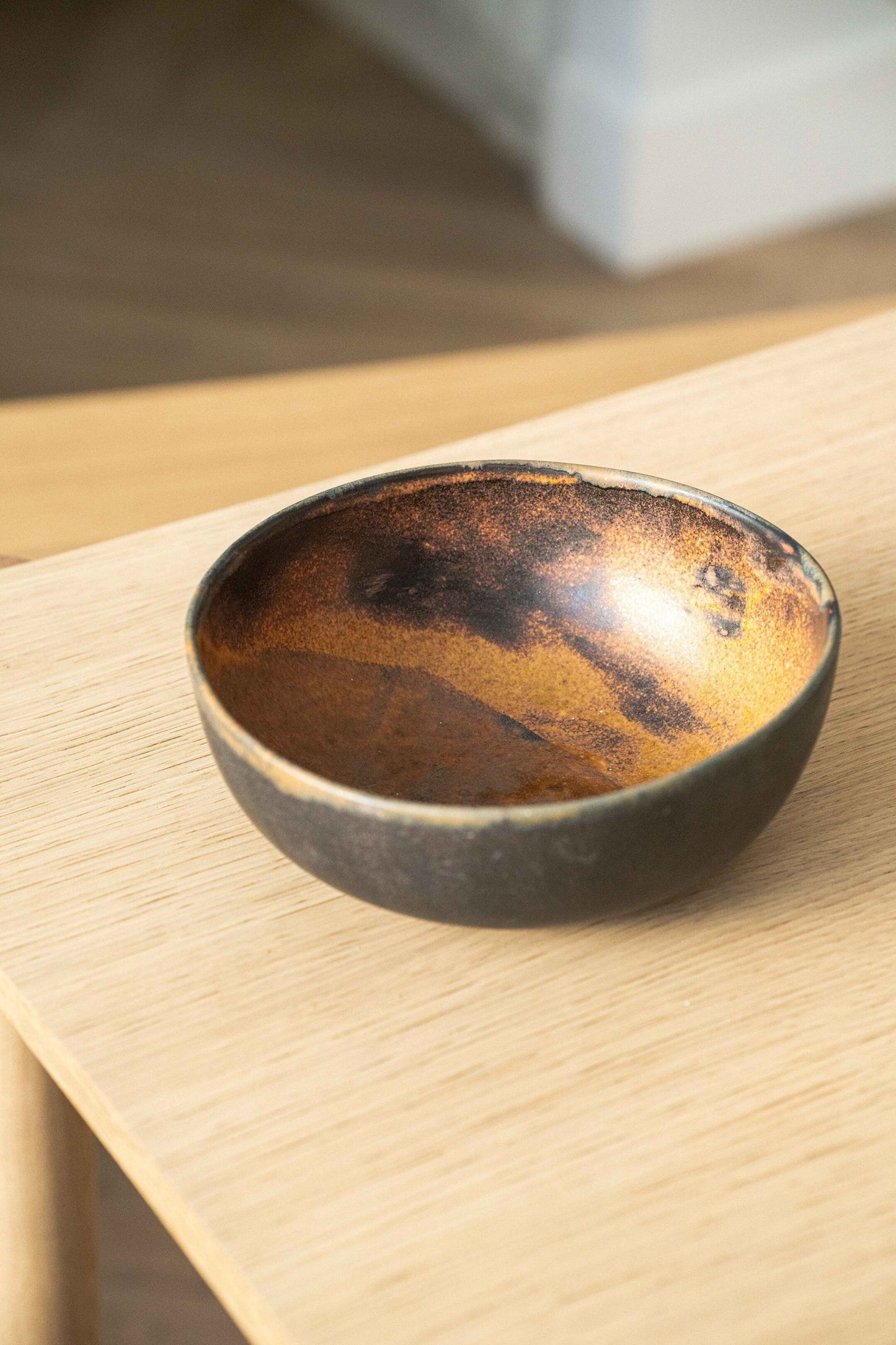 Rust stoneware nesting bowl set with matte brown-black glaze and unique swirls stacked on white background