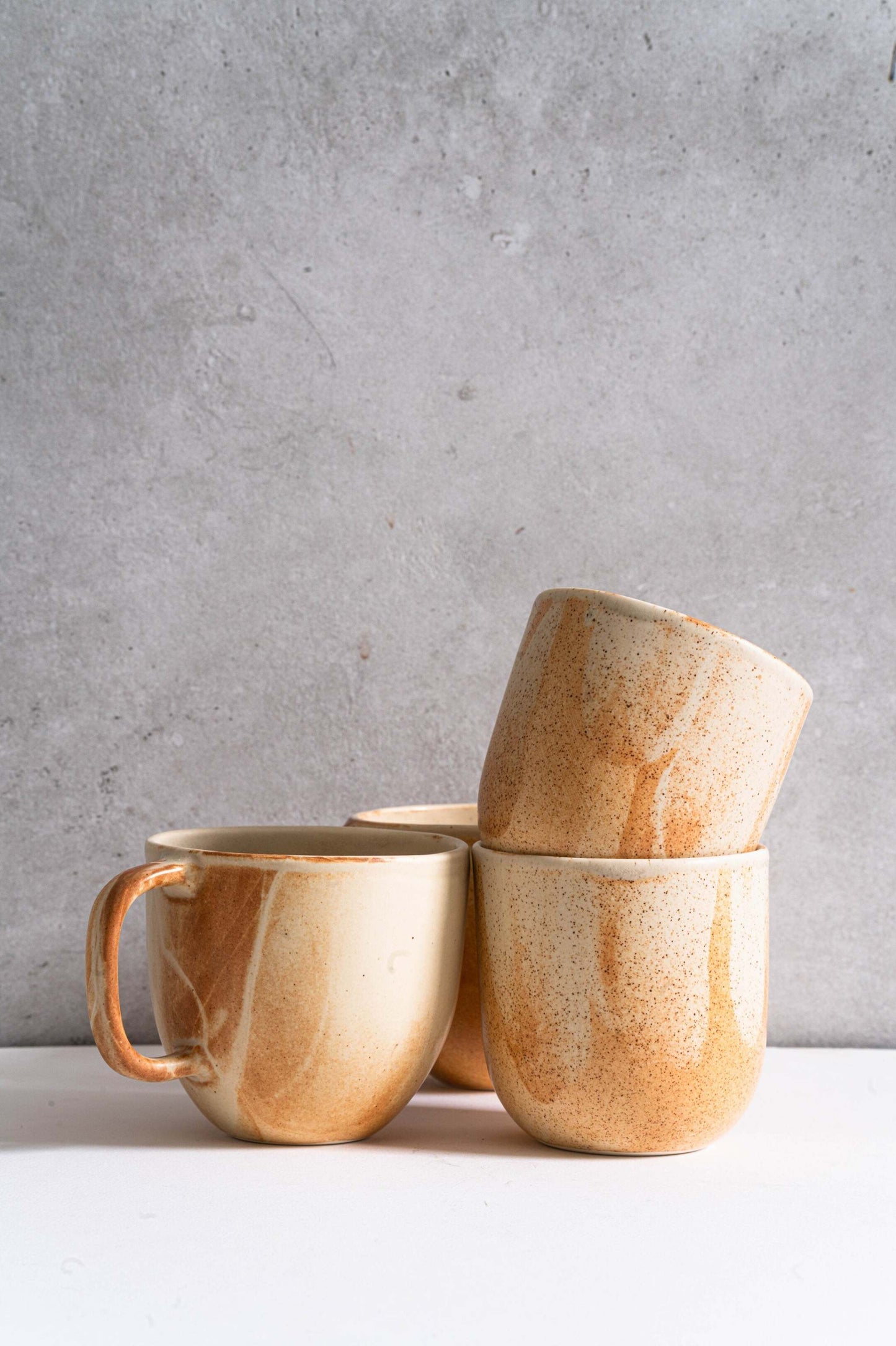 Handmade stoneware beige coffee mug with unique reactive glaze and rust drips, microwave and dishwasher safe.