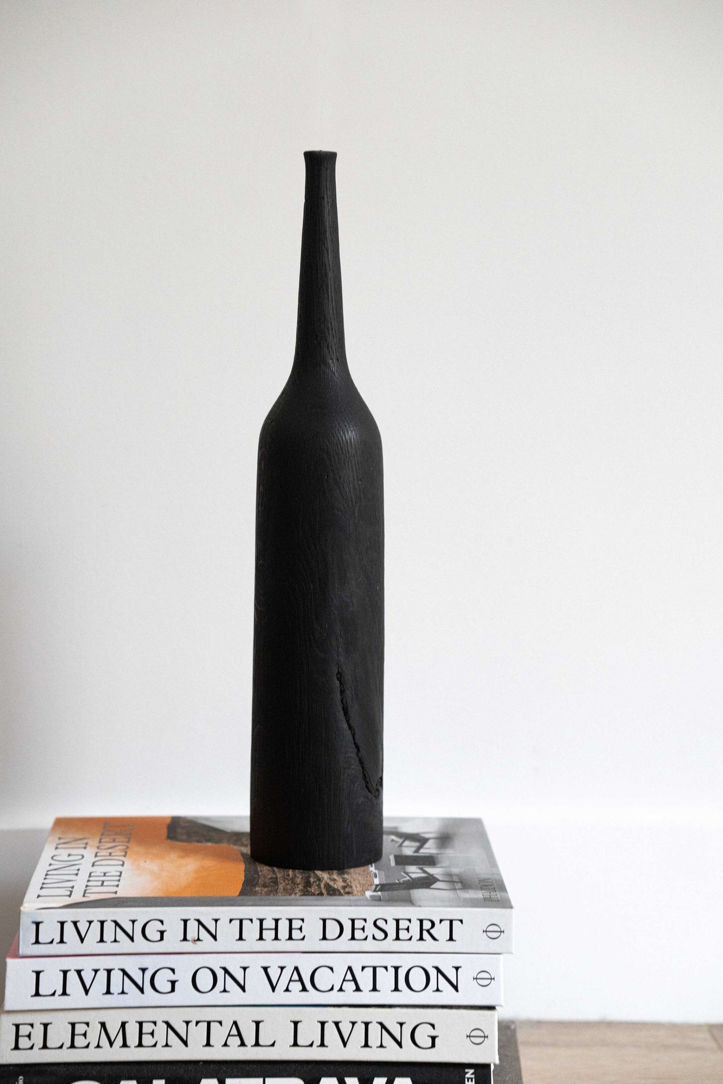 Tall charred wood vase with sharp shoulders and long neck, handcarved from oakwood, rustic modern design.