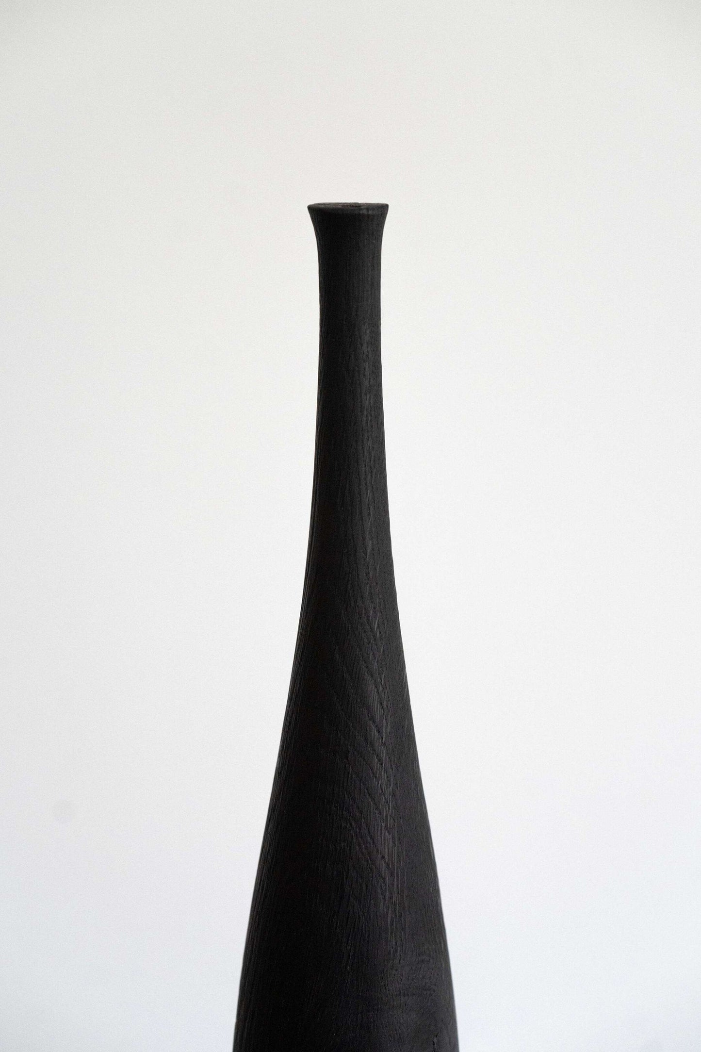 Tall charred wood vase with sharp shoulders and long neck handcrafted from oakwood