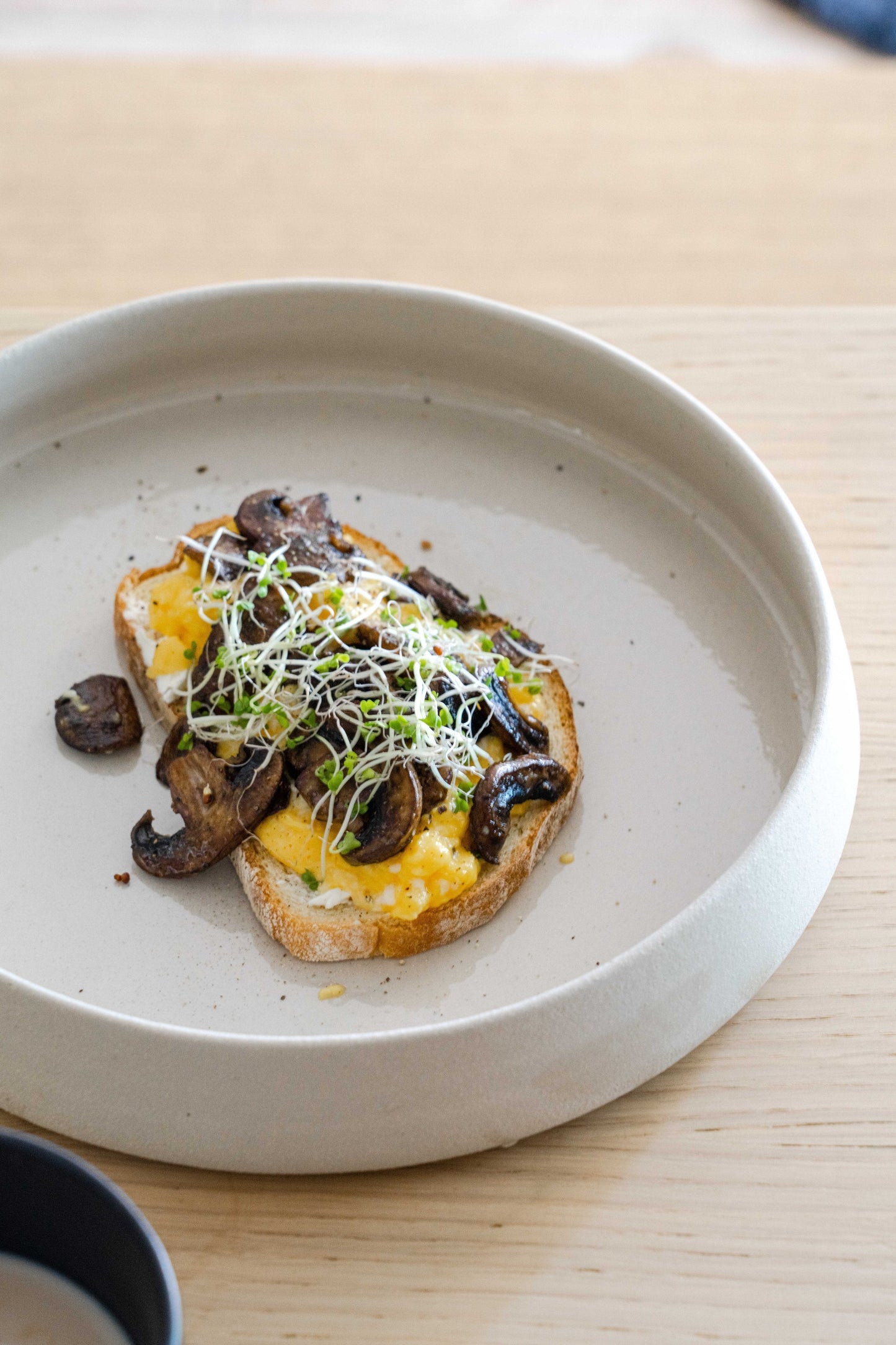 Handmade stoneware dinner plate with high sides and transparent glaze showing rustic texture