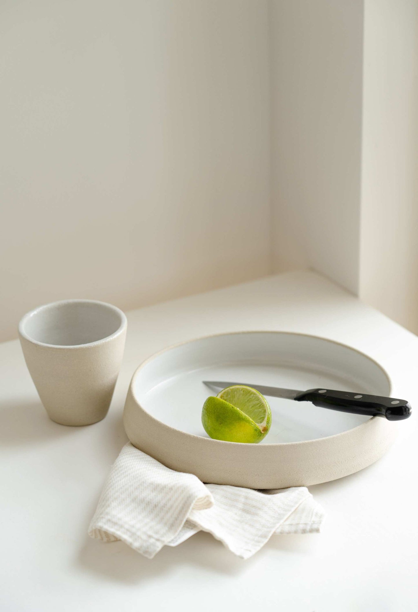 Handmade stoneware dinner plates with high sides featuring textured exterior and glossy white interior glaze