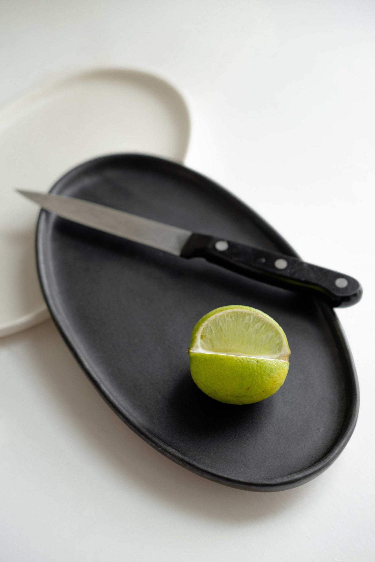 Handmade black matte stoneware oval serving platter with organic edges and reactive glaze
